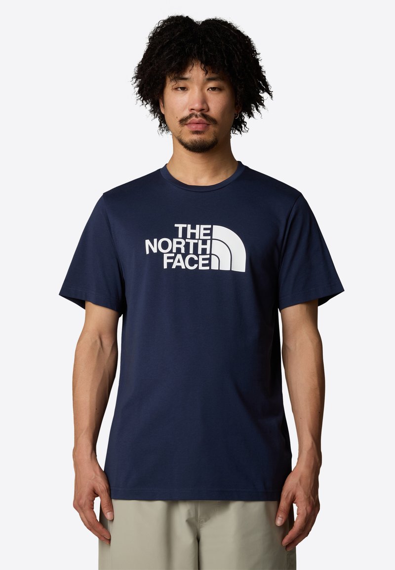 Navyblaue Baumwoll-T-Shirt mit einem weißen Logo mit geschwungenen Elementen. Kurze Ärmel, runder Ausschnitt und klassisches Schnittdesign mit minimaler Textur.