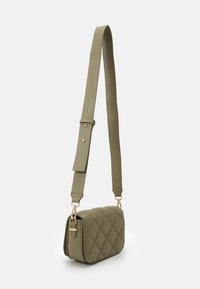 Prošívaná olivově zelená crossbody taška s nastavitelným širokým popruhem a zlatým kováním na bílém pozadí.