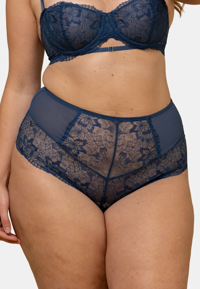 Ensemble soutien-gorge en dentelle bleu marine et culotte taille haute, mettant en avant des motifs floraux, des textures transparentes et des accents délicats en dentelle.