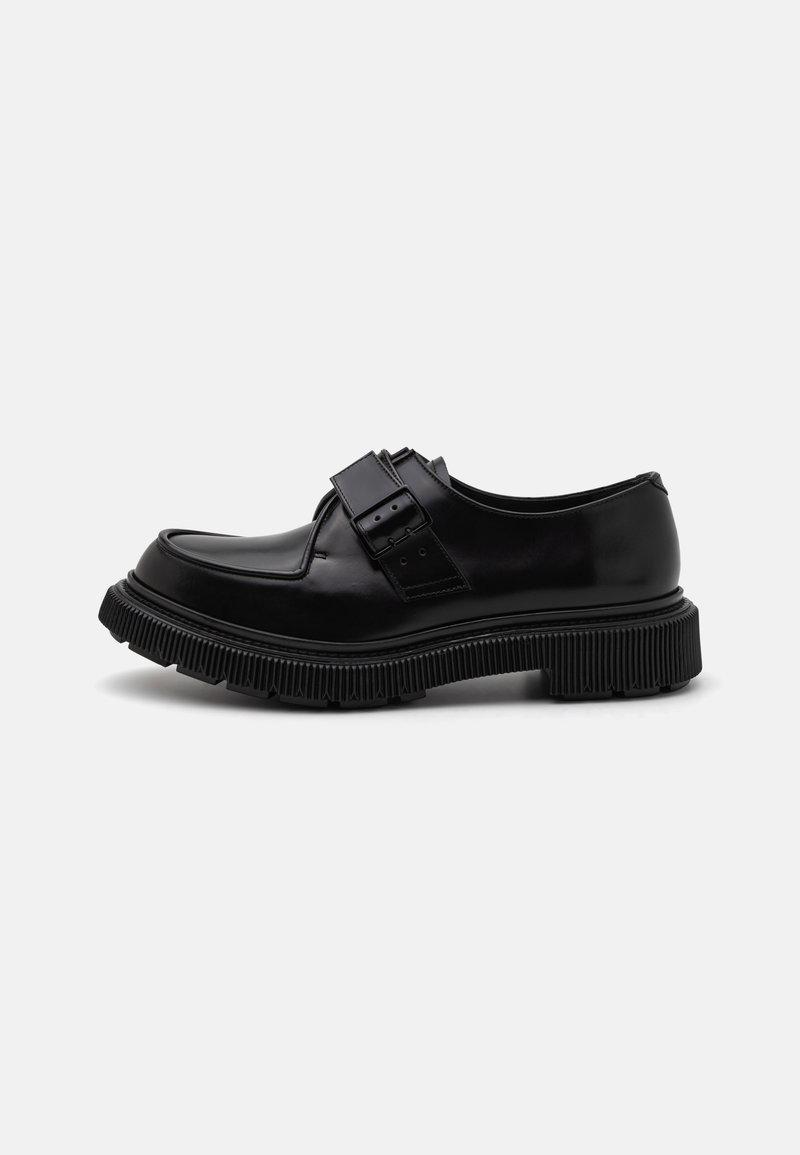 Pantofi din piele neagră cu vârful rotunjit, curea cu cataramă și talpă groasă cu nervuri. Finisaj neted cu un design minimalist și fără motive suplimentare.