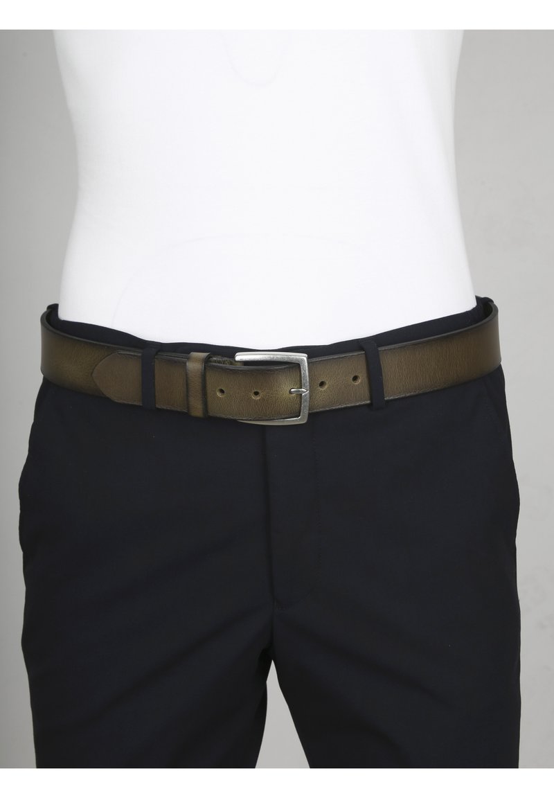 Bruine leren riem met een gladde textuur, een zilveren metalen gesp en meerdere gaatjes voor maataanpassing, gedragen met donkere broek.