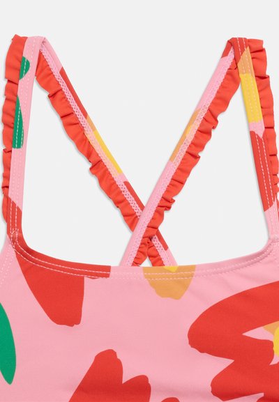 Ροζ ύφασμα με έντονο κόκκινο, πράσινο και κίτρινο αφηρημένο λουλουδάτο σχέδιο, με σταυρωμένους ραμμένους ιμάντες ώμου με λευκή ραφή.