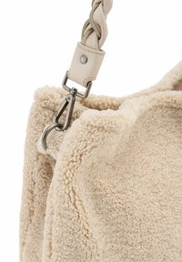 Borsa shaggy beige con un tessuto testurizzato, dotata di una tracolla in pelle intrecciata e un gancio in metallo per l'attacco. Esterno morbido e vellutato.