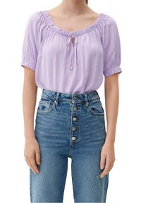 Lavender blouse with short, gathered sleeves and a tie closure. Paired with high-waisted blue denim jeans featuring a button front.