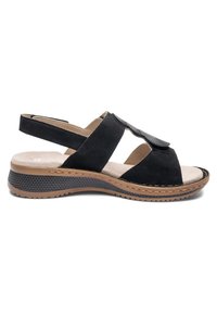 Schwarze offene Sandale mit verstellbarem Riemen, gepolstertem beigem Innenfutter und niedriger, strukturierter Sohle für Komfort und Halt.