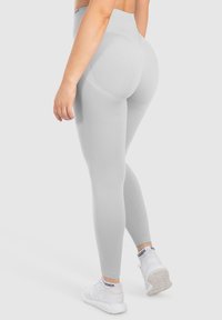 Szare legginsy typu high-waisted wykonane z elastycznego materiału, o gładkiej fakturze i skonturowanym kroju zapewniającym lepsze dopasowanie.