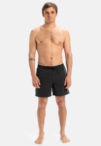 Bañador negro con cintura elástica, que presenta una textura suave, dos rayas laterales y un corte regular.