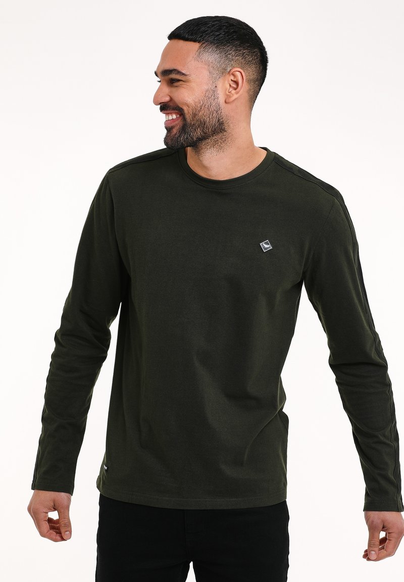 Camicia a maniche lunghe di colore verde oliva realizzata in tessuto morbido, con scollatura a girocollo e una piccola etichetta con logo sul lato sinistro del petto.