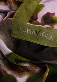 Pañuelo floral ligero y transparente con tonos de rosa, verde y marrón, con borde cosido y etiqueta de marca en la esquina.