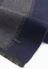 Uldscarf med et navy og grå farveblok design, glat tekstur, frynser i kanten og et lille sort label med tekst.