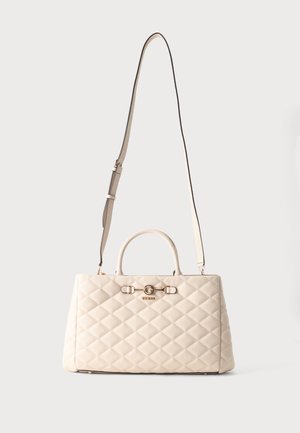 Sac à main matelassé crème avec des poignées courtes et une longue bandoulière ajustable, featuring un petit logo doré et des garnitures décoratives à l'avant.