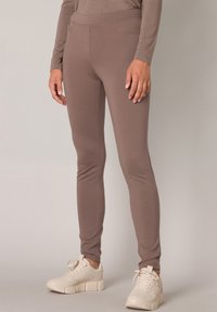 Lichtbruine strakke leggings gemaakt van zacht, rekbaar materiaal, met een hoge tailleband, voorzakken en een gladde textuur.