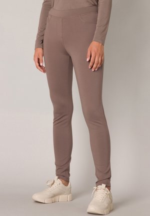 Lichtbruine strakke leggings gemaakt van zacht, rekbaar materiaal, met een hoge tailleband, voorzakken en een gladde textuur.