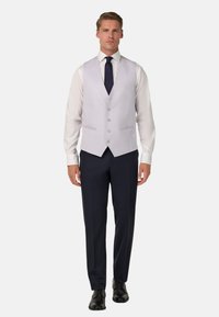 Jasnoszara kamizelka na białej koszuli, w połączeniu z ciemnogranatowymi spodniami. Posiada klasyczny krój, pięć guzików i brak widocznych wzorów.