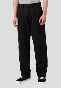 Pantalons noirs en coton à coupe décontractée, avec des poches avant et des éléments en métal argenté. Associés à des baskets noires, adaptés pour un look décontracté.