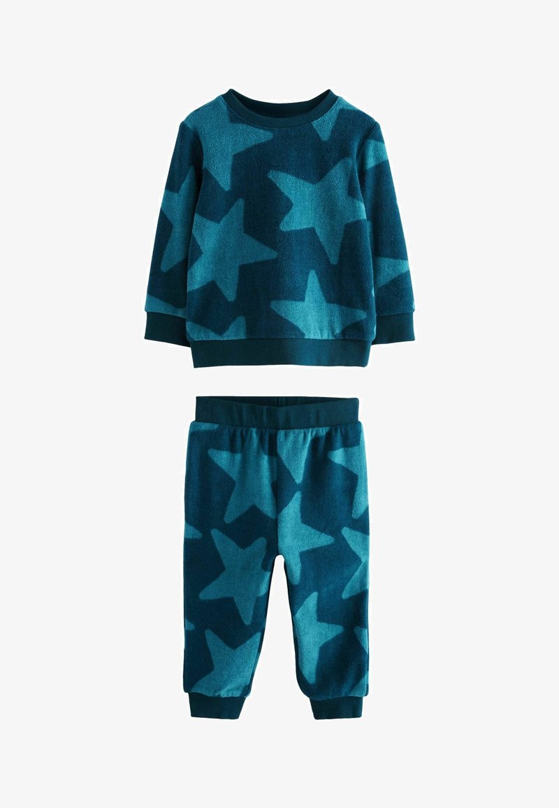 Set di abbigliamento da casa in pile color teal, caratterizzato da grandi e audaci motivi a stella. La maglia ha maniche lunghe e polsini a costine; i pantaloni presentano un elastico in vita.