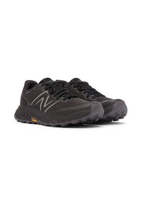 Pair of black New Balance running shoes with textured soles and laces, designed for trail running with Vibram outsole.