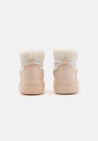 Botte imperméable rose avec un col en fausse fourrure blanche, des lacets blancs et une semelle en caoutchouc robuste. Dispose d'une languette à l'arrière.