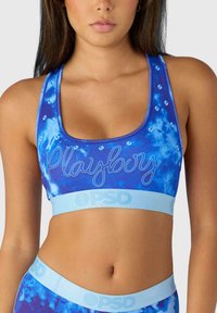 Sinise sinine tie-dye spordirinnahoidja, millel on ümmargune kaelus, kaunistatud "Playboy" logoga ja kerge sinine elastne riba brändingu kujutisega.