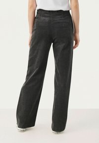 Mustat corduroyt, leveät lahkeet, tekstuuripinta, kaksi takataskua ja korkea vyötärö, yhdistetty valkoisiin tennareihin.