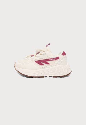 Lavtop beige sneaker med lyserøde accenter, tyk hvid sål, snørelukning foran og ordet "SHADOW" på siden.
