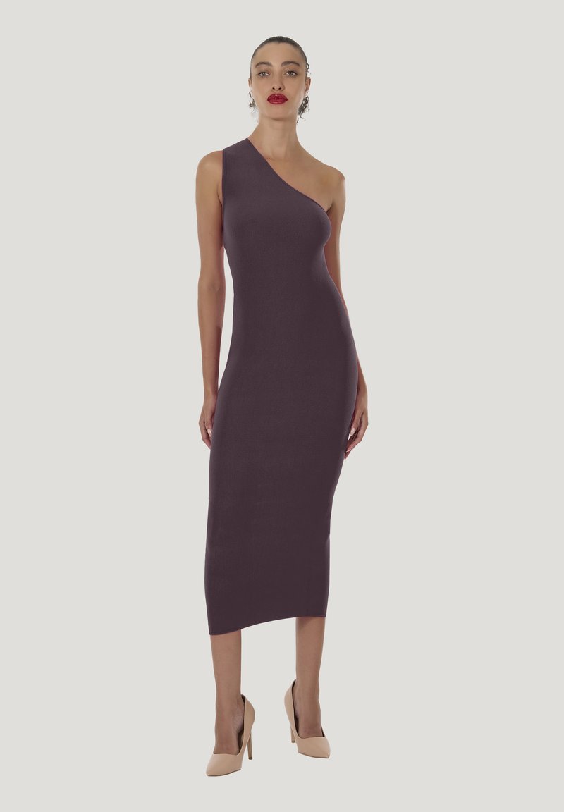 Asymmetrisches lila Strickkleid in Midi-Länge und figurbetontem Schnitt, kombiniert mit hautfarbenen High Heels. Glatte Textur, minimalistische Details.