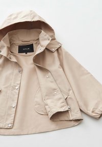 Giacca leggera beige con cappuccio, tessuto impermeabile, hardware argentato, bottoni a scatto e tasca frontale. Tessuto morbido, vestibilità leggermente oversize.