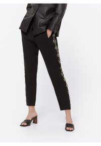 Zwarte broek met versierde side-details, waaronder kralen en bloemmotieven. Slim-fit ontwerp met een gladde stoftextuur.