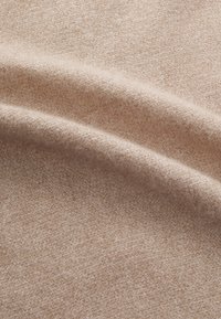 Tissu doux et beige avec un tissage fin et texturé ; une variation subtile de ton renforce la profondeur et l'intérêt visuel. Lisse au toucher.