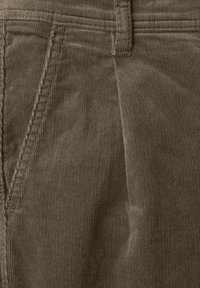 Brązowa tkanina kordurowa z pionowymi wypustkami, z przednią kieszenią i przeszywaną talią. Tekstura wydaje się miękka i trwała.