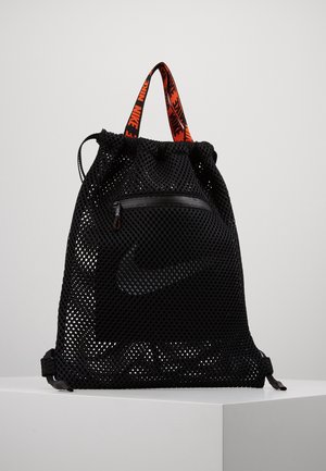 Black mesh Nike drawstring backpack with front zipper pocket and orange Nike logo straps, displayed on white pedestal.