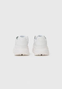 White sneakers with a smooth leather upper, rounded toe, padded collar, and thick, textured rubber sole. Minimalist design, no visible branding.