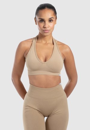 Beige sportbh met een diepe V-hals, geribbeld textuur en verstelbare bandjes. Gecombineerd met hoge geribbelde legging in dezelfde kleur.