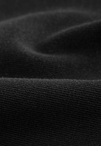 Acercamiento de una tela negra texturizada, que muestra contornos suaves y finas estrías, creando una apariencia suave y elegante.