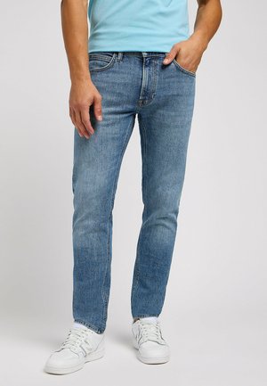 Blaue Jeans aus Denim mit geradem Schnitt und mittlerem Waschdesign. Verfügt über fünf Taschen, Gürtelschlaufen und subtile Nähte. Trägt man mit weißen Sneakers.