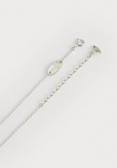 Duas correntes de prata delicadas com estilos de fecho diferentes, uma apresentando um pequeno pingente oval gravado com um design estilizado de orbe e cruz.