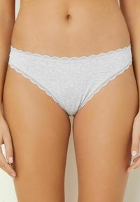 Thong din bumbac gri cu o margine dantelată ondulată pe talie și pe deschiderea picioarelor. Textură moale cu un design ușor.