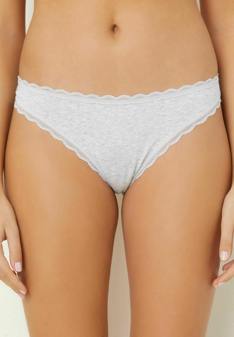 Thong din bumbac gri cu o margine dantelată ondulată pe talie și pe deschiderea picioarelor. Textură moale cu un design ușor.