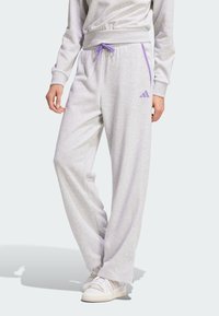 Jasnoszare dresowe spodnie z bawełny charakteryzują się luźnym krojem, elastycznym pasem w kolorze purpurowym z purpurowym sznurkiem i purpurowymi paskami po bokach, ozdobionymi logo Adidas.