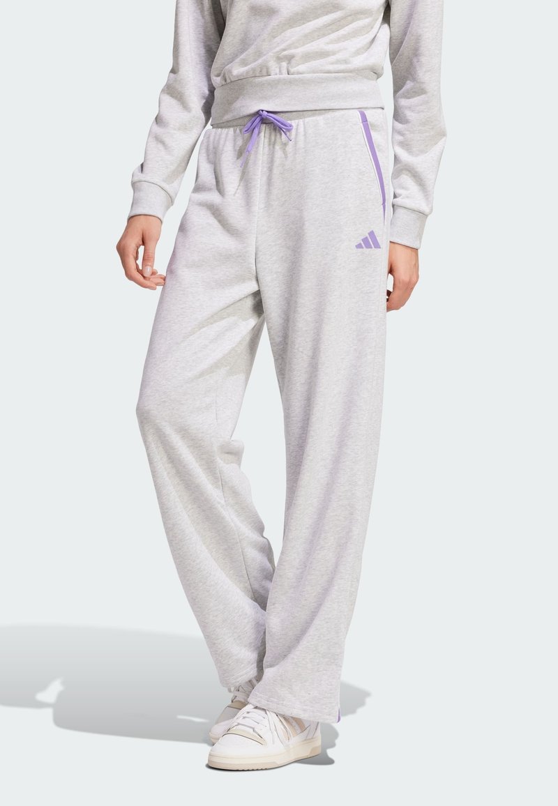Jasnoszare dresowe spodnie z bawełny charakteryzują się luźnym krojem, elastycznym pasem w kolorze purpurowym z purpurowym sznurkiem i purpurowymi paskami po bokach, ozdobionymi logo Adidas.