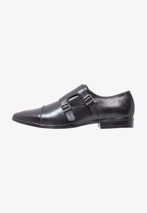 Chaussure de ville pour homme en cuir noir avec un bout pointu, double boucle de monk, et boucles en métal argenté, présentée de l'extérieur.
