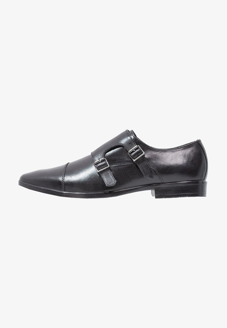 Chaussure de ville pour homme en cuir noir avec un bout pointu, double boucle de monk, et boucles en métal argenté, présentée de l'extérieur.