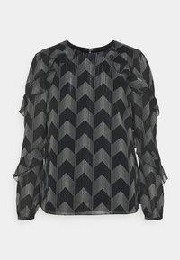 Schwarze Bluse mit einem Zickzackmuster aus weißen Punkten. Verfügt über Rüschendetails an den Ärmeln und einen runden Ausschnitt. Hergestellt aus leichtem, durchscheinendem Stoff.