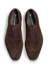 Scarpe derby in suede marrone con perforazioni decorative, lacci blu e una suola nera elegante. Presentano una punta rotonda e dettagli di cucitura.
