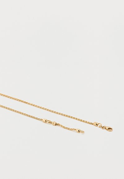 Kultainen ketjukaulakoru, jossa on kiemurteleva muotoilu ja pienet pallomaiset korostukset, varustettu turvallisella lukolla ja sileällä pinnalla.