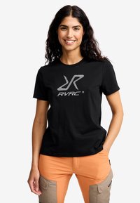 Svart bomull t-shirt med en silver RVRC-logotyp, i kombination med orange arbetsbyxor med khaki-accenter och flera sidfickor.