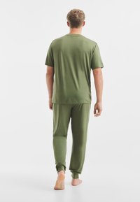 Set di abbigliamento per il tempo libero verde oliva composto da una T-shirt a maniche corte e pantaloni con elastico in vita, entrambi realizzati in tessuto morbido e leggero.