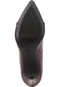 Scarpa con tacco alto in pelle bordeaux con punta affilata. La suola è in gomma nera con un design perforato, caratterizzata da un logo sul tacco.