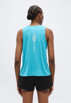 Γυναίκα με πλεξούδες σε κότσο φοράει μπλε αμάνικο αθλητικό τοπ με το κείμενο «Never Stop Running» στην πλάτη και μαύρο αθλητικό σορτς.