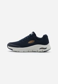 Scarpa da atletica Skechers in mesh sintetico blu navy con suola imbottita bianca, caratterizzata da dettagli del logo oro e design testurizzato.